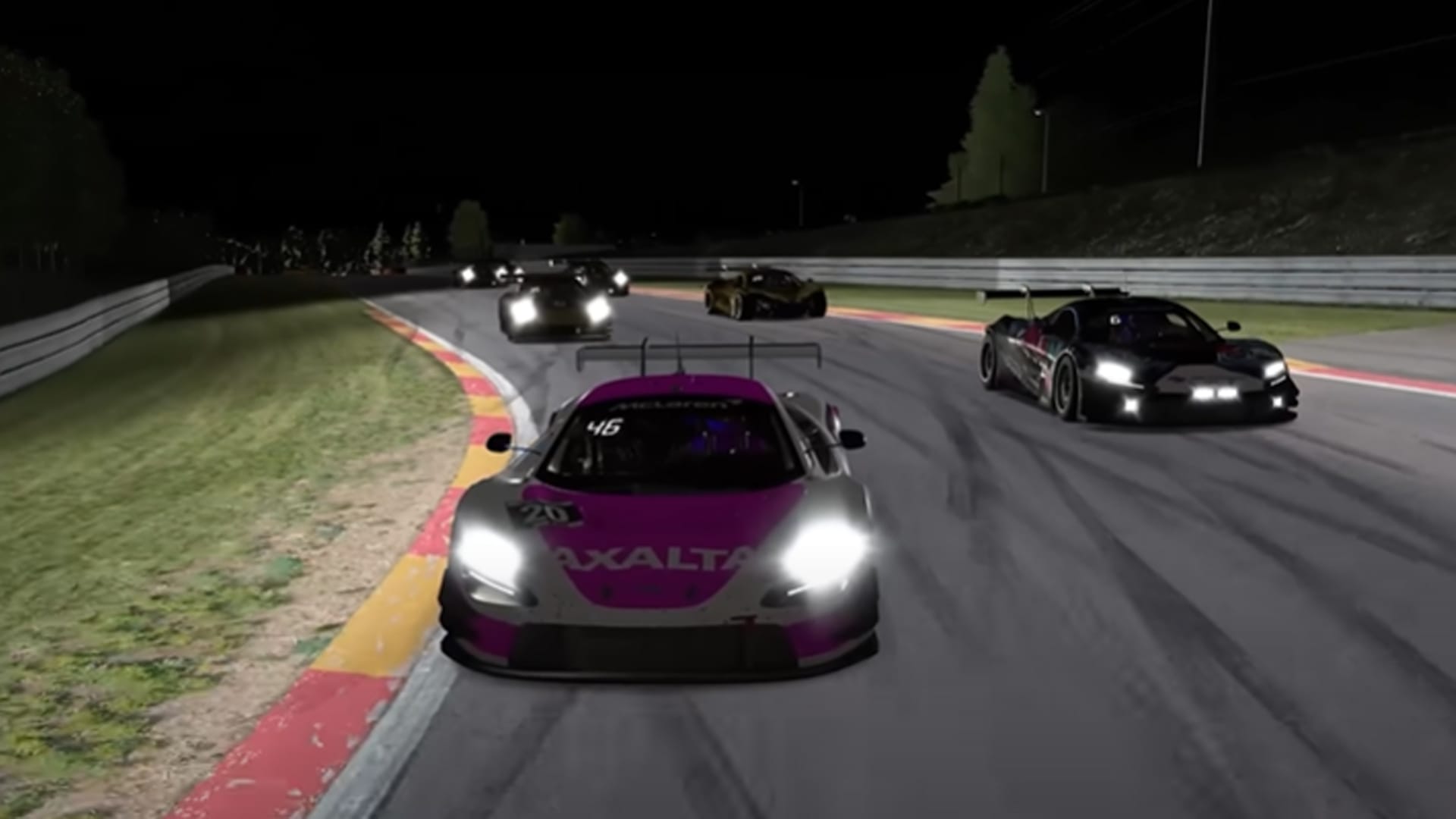 The front of a pink and white McLaren 720S GT3 race car leading a train of about six or so other race cars around a race track at night, with all their headlights on.