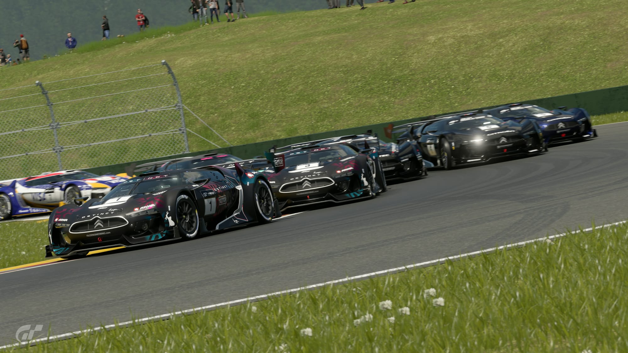 A bunch of GT by Citroen race cars go through the hairpin section at the start of Autodromo Lago Maggiore. The leading two are black, with pale maroon and teal accents.