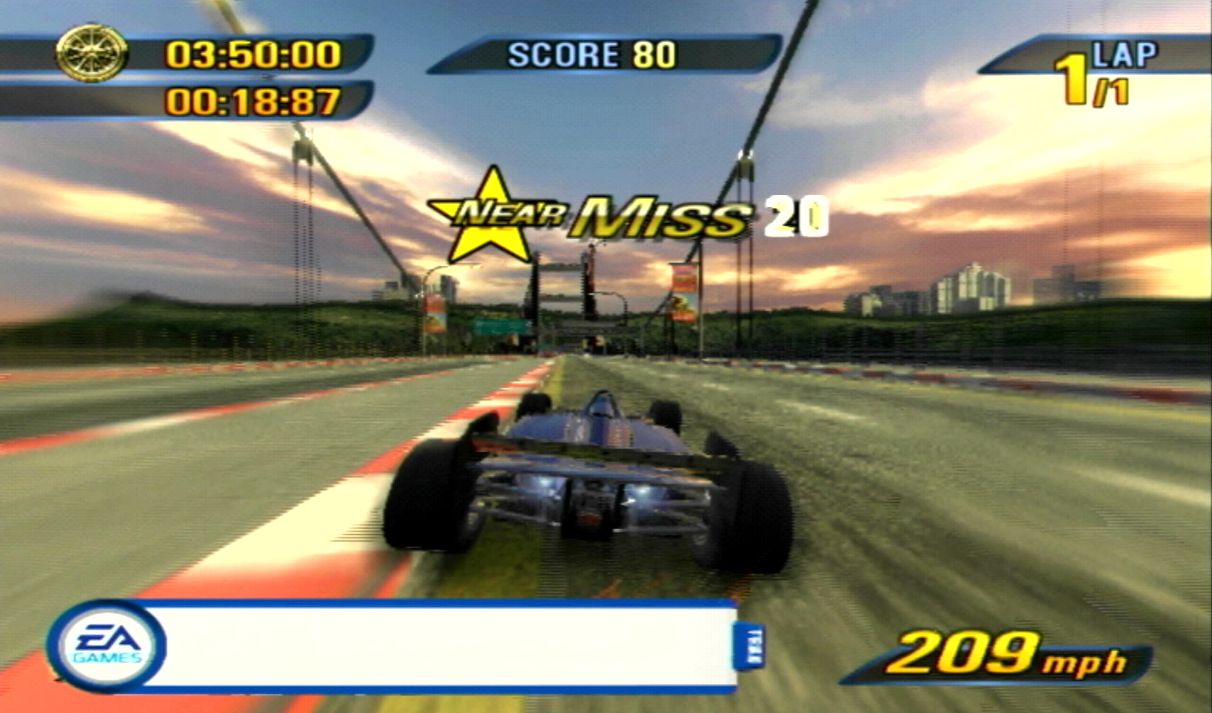 A burning lap time trial event in Burnout 3: Takedown featuring the US Circuit Racer. It is at it's max boost speed and the world is zooming on by, with an array of blues and oranges in the evening sky. The EA Trax bar is on screen, but the song hasn't been displayed yet.