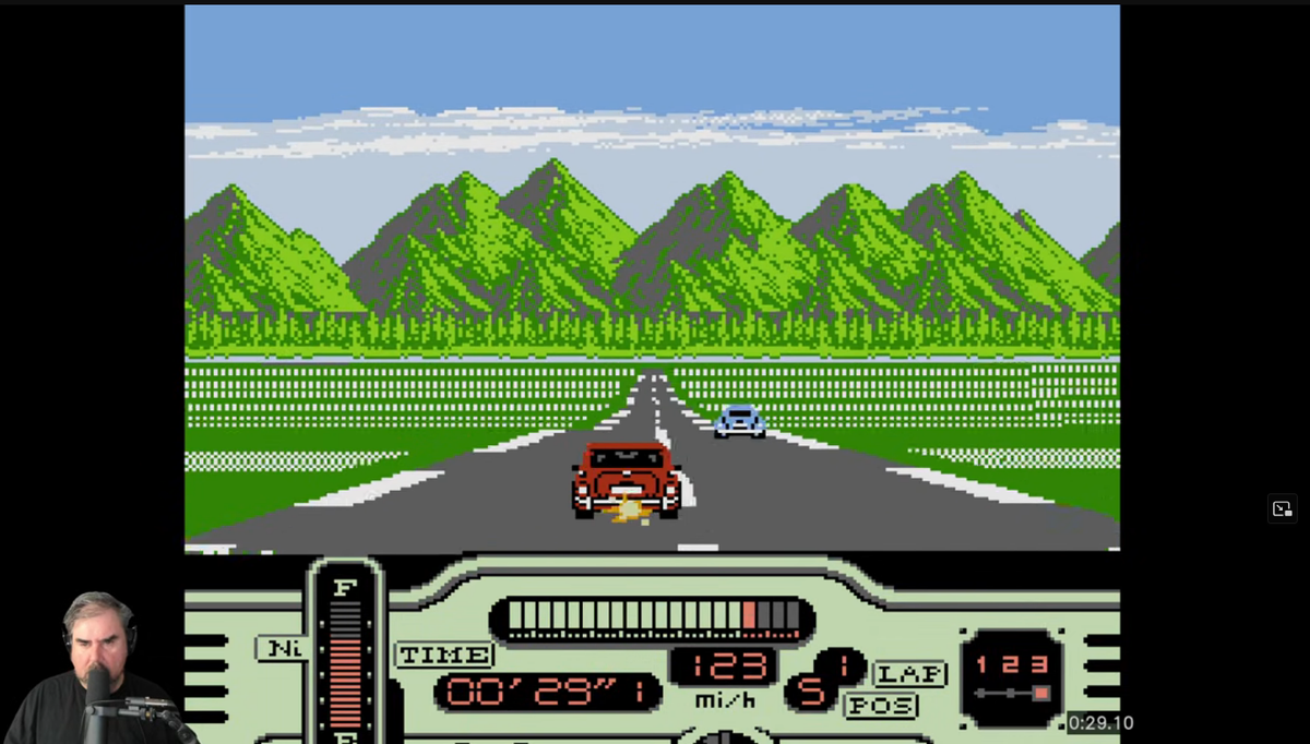 Gameplay of Formula 1: Built to Win, with a Mini Cooper splitting flames out of it's exhaust at a forested track. Jeff Gertsmann is in the corner, locked in.