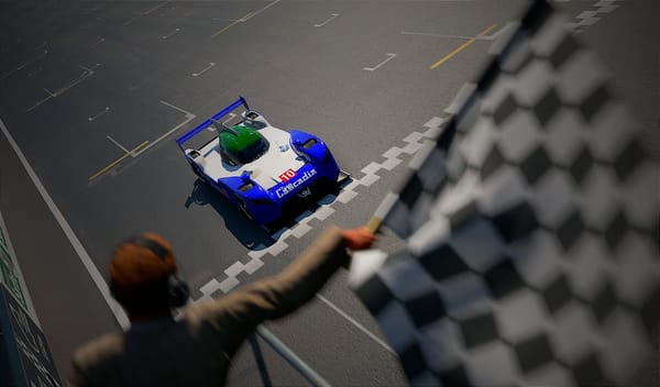 A blue, white and green Nissan GT-R LM NISMO race car crossing the finish line at a race, from the perspective of the flag man.